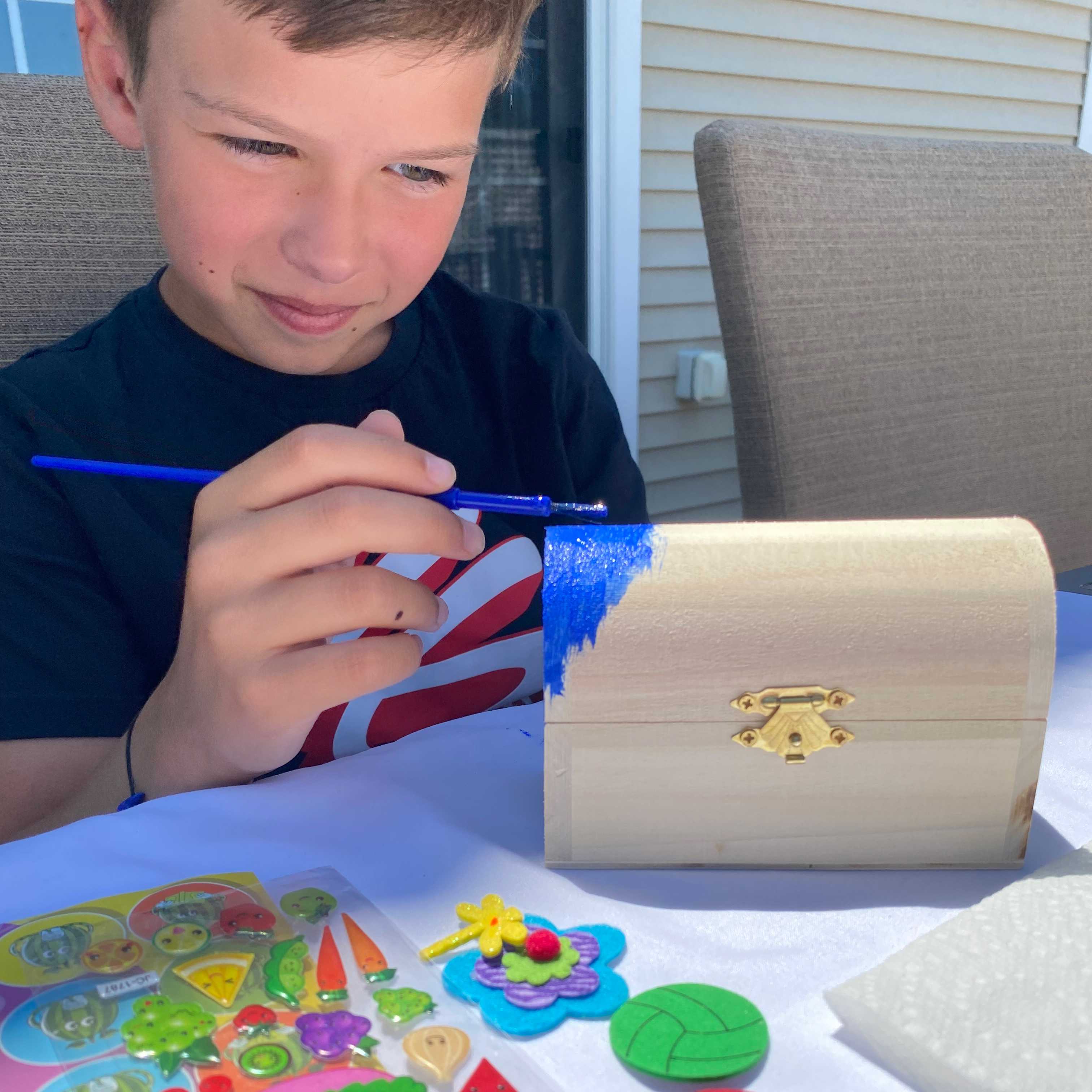 child paints wooden box